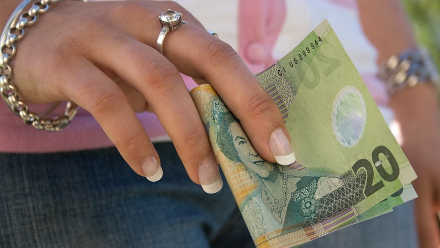 A woman uses a NZ$20 note